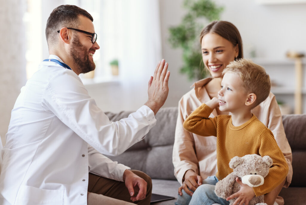 family doctor pediatrician conducts examination of child boy and giving high five to him